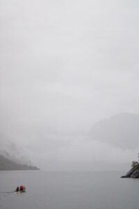 Small boat on frosty lake on foggy day.