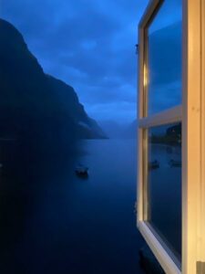 Looking out window at boat on lake at night.